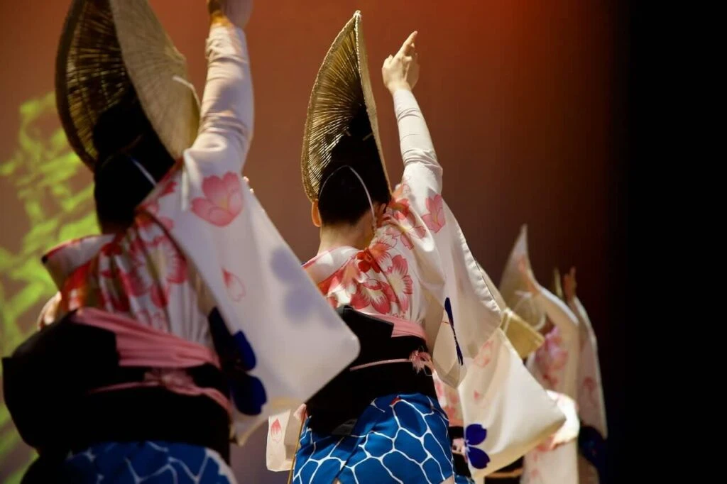 Dancers carry the same pulse with raised hands.
